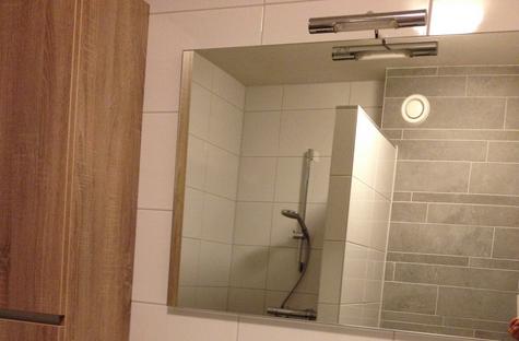 Een grote spiegel geeft in een kleine badkamer een ruimtelijk effect.